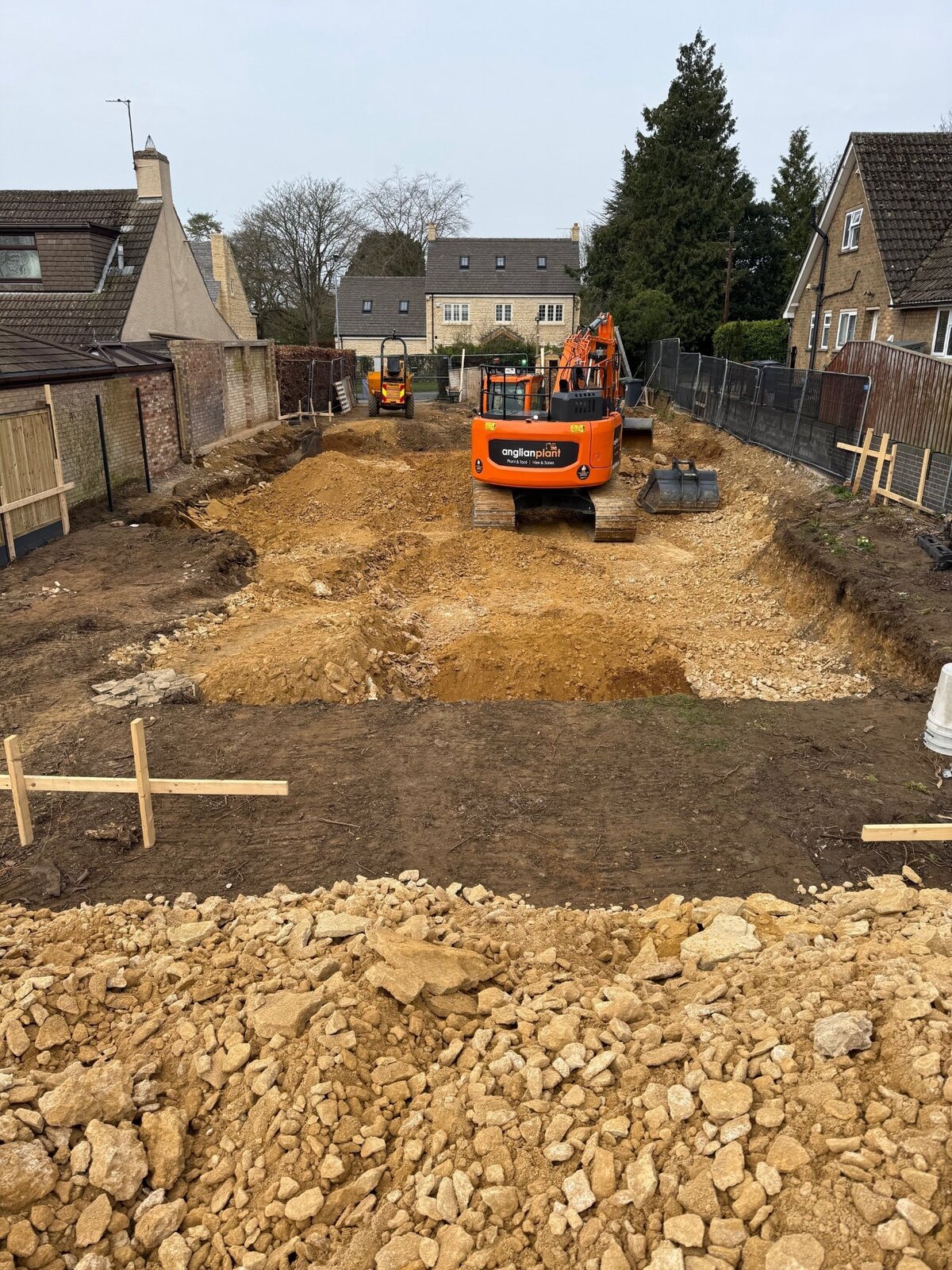 New build groundworks with excavator and foundation trenches