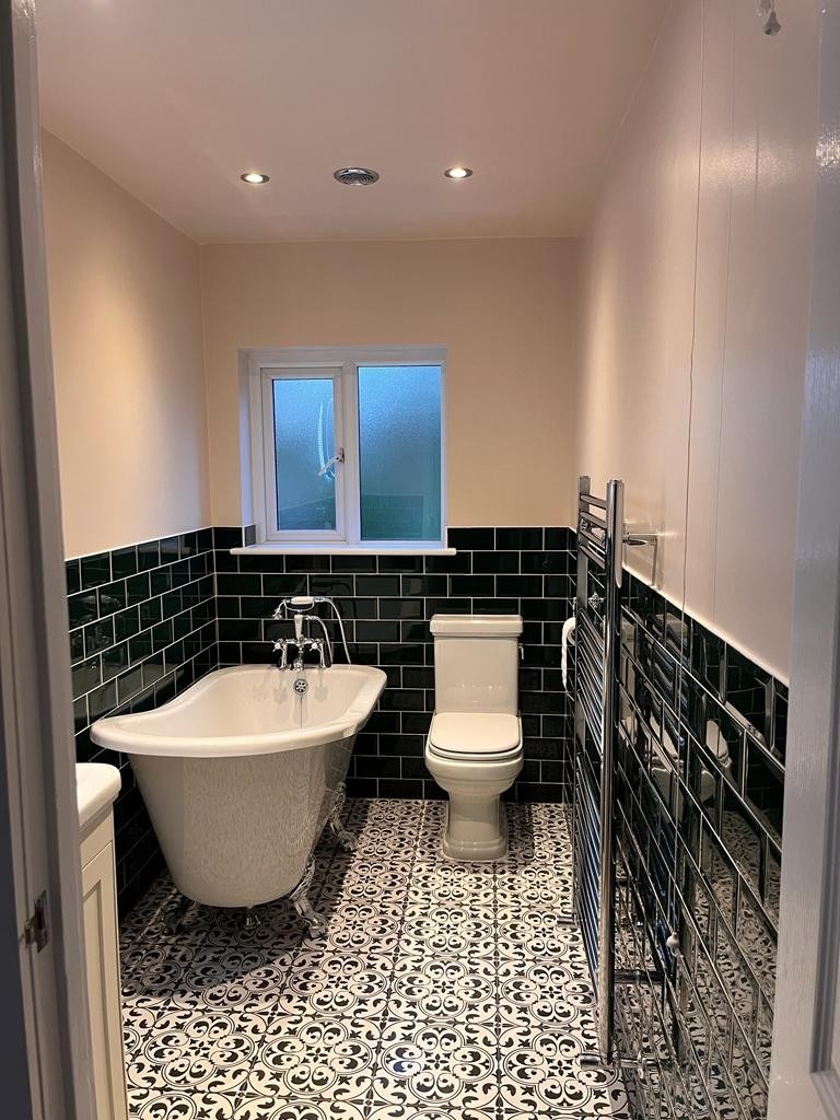 Bathroom with freestanding roll-top bath, dark metro tiles and patterned floor