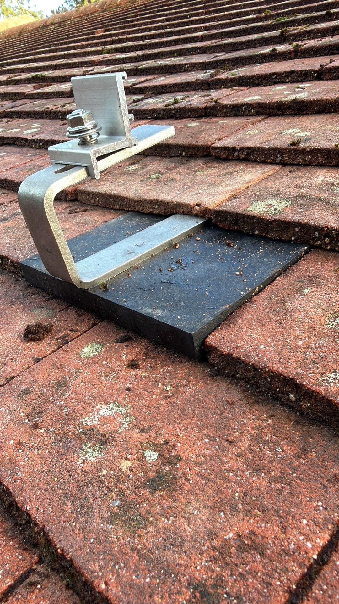Close up of solar panel roof hook mounting on clay tiles